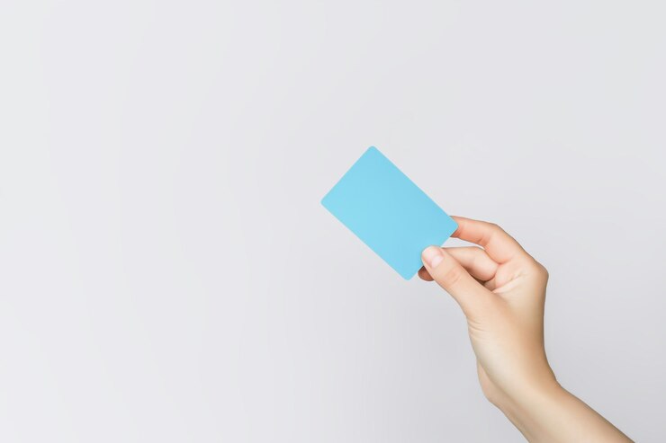 Foto mano sosteniendo una tarjeta de plástico azul sobre un fondo gris