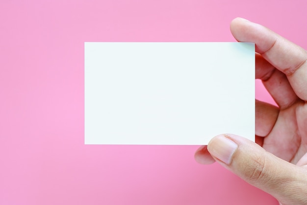 Mano sosteniendo tarjetas en blanco sobre fondo rosa