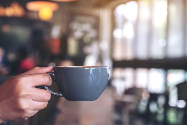 mano sosteniendo una taza azul de café caliente