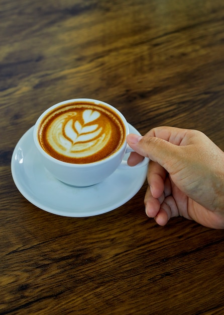 Mano sosteniendo la taza de café en la mesa