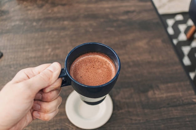 Mano sosteniendo una taza de chocolate caliente en un café