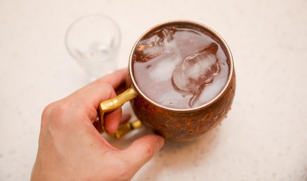 Una mano sosteniendo una taza de cobre con una bebida