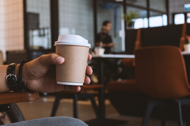 mano sosteniendo la taza de papel de café en café