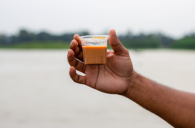 Una mano sosteniendo una taza de té en el río con modo relajante.