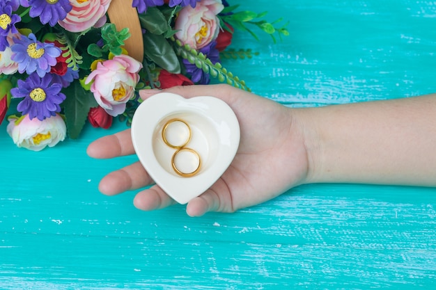 Foto mano sosteniendo un tazón de corazón y un anillo de bodas