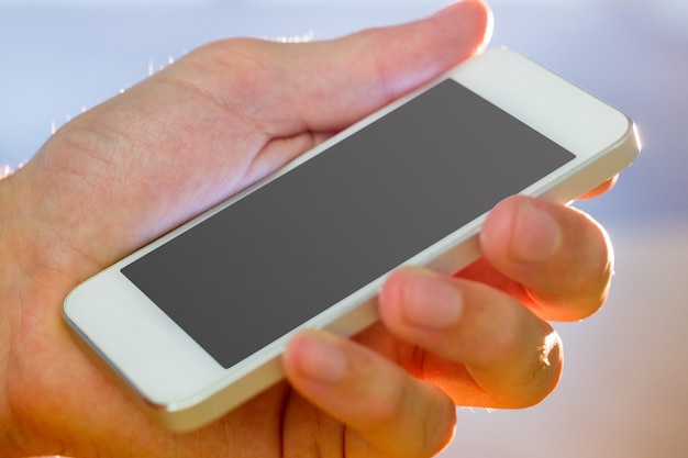 Foto mano sosteniendo un teléfono inteligente blanco