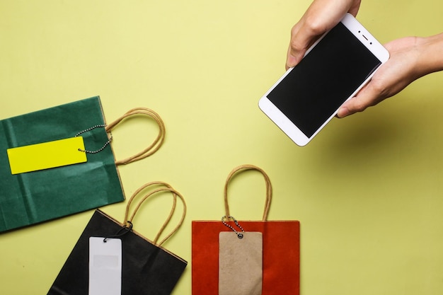 Foto mano sosteniendo un teléfono inteligente entre bolsas de compras. concepto de compras.