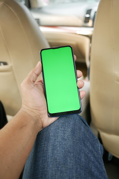 Mano sosteniendo un teléfono inteligente con pantalla vacía en un auto