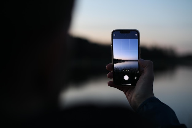 Mano sosteniendo un teléfono inteligente y tomando una foto de la hermosa puesta de sol