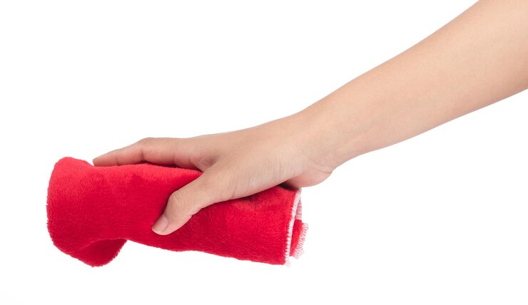 Foto mano sosteniendo toallitas rojas de microfibra aislado sobre fondo blanco.
