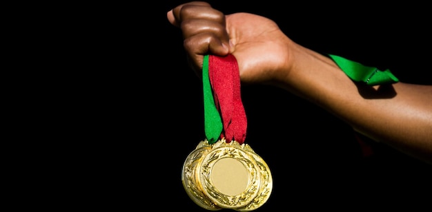 Mano sosteniendo tres medallas de oro sobre fondo blanco.