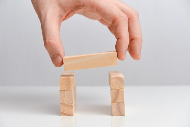 La mano sostiene el bloque de madera en dos bloques de madera