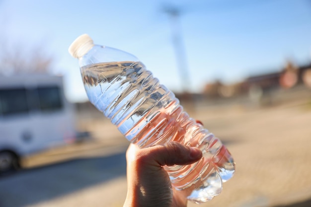 Una mano sostiene una botella de agua que dice "agua" en ella