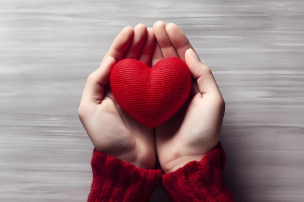 La mano sostiene un corazón de punto rojo