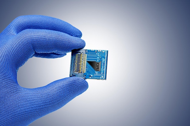 Foto la mano sostiene una cpu contra el fondo azul gris concepto de producción o reparación de chips electrónicos sistema de pc enfoque selectivo