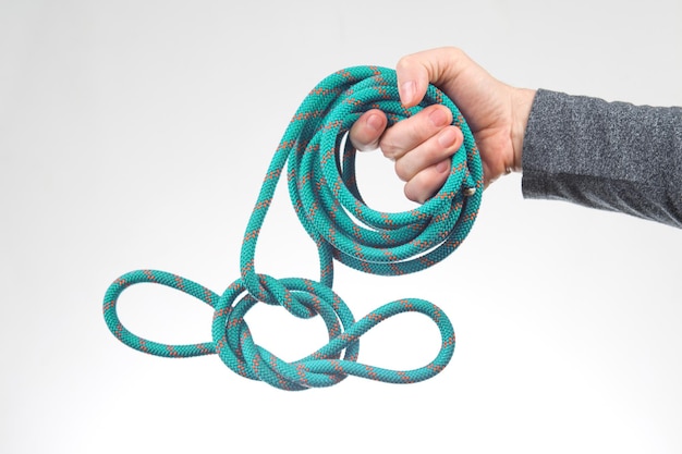 La mano sostiene la cuerda de color para el artículo del equipo de escalada para acampar y escalar