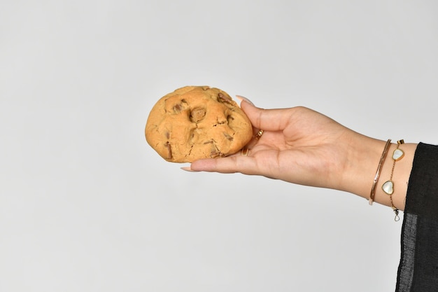 Foto una mano sostiene una galleta con un fondo blanco.