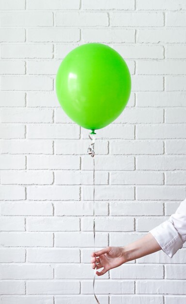 La mano sostiene el globo verde en la cinta.