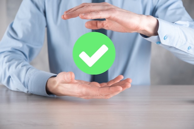 Foto la mano sostiene el icono verde marca de verificación, signo de marca de verificación, icono de tic, signo derecho, botón de marca de verificación verde del círculo, listo. sobre fondo oscuro. bandera. espacio de copia. lugar para el texto.