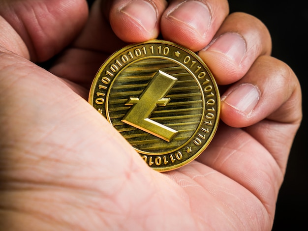 Mano sostiene oro litecoin.