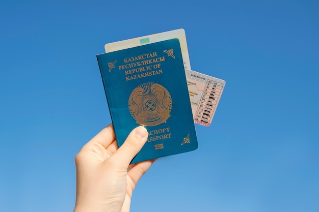 Mano sostiene el pasaporte nacional de la República de Kazajstán contra el fondo del cielo azul