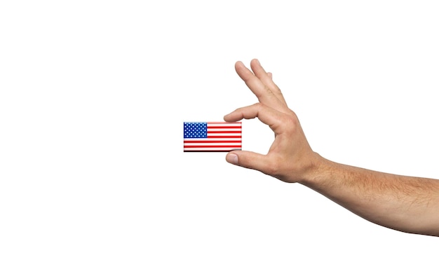 Mano sostiene una pequeña bandera americana sobre fondo blanco.