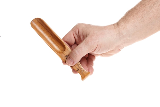 La mano sostiene una pequeña cuchara de madera para cereales sobre un fondo blanco.