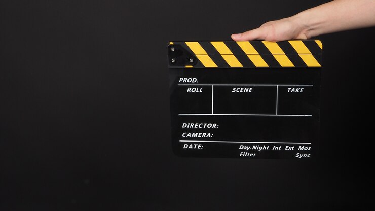Foto la mano sostiene la pizarra de películas de color amarillo y negro. se utiliza en la producción de video y la industria cinematográfica sobre fondo negro.
