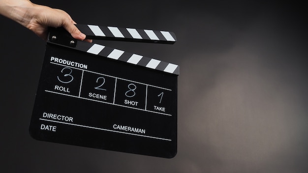 Una mano sostiene el tablero de azote negro o el uso de la pizarra de películas en la producción de video, películas, cine, industria del cine sobre fondo negro. Ha escrito en número.