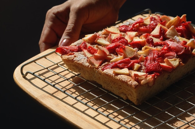 Una mano sostiene un trozo de pastel de frutas con la palabra manzana.