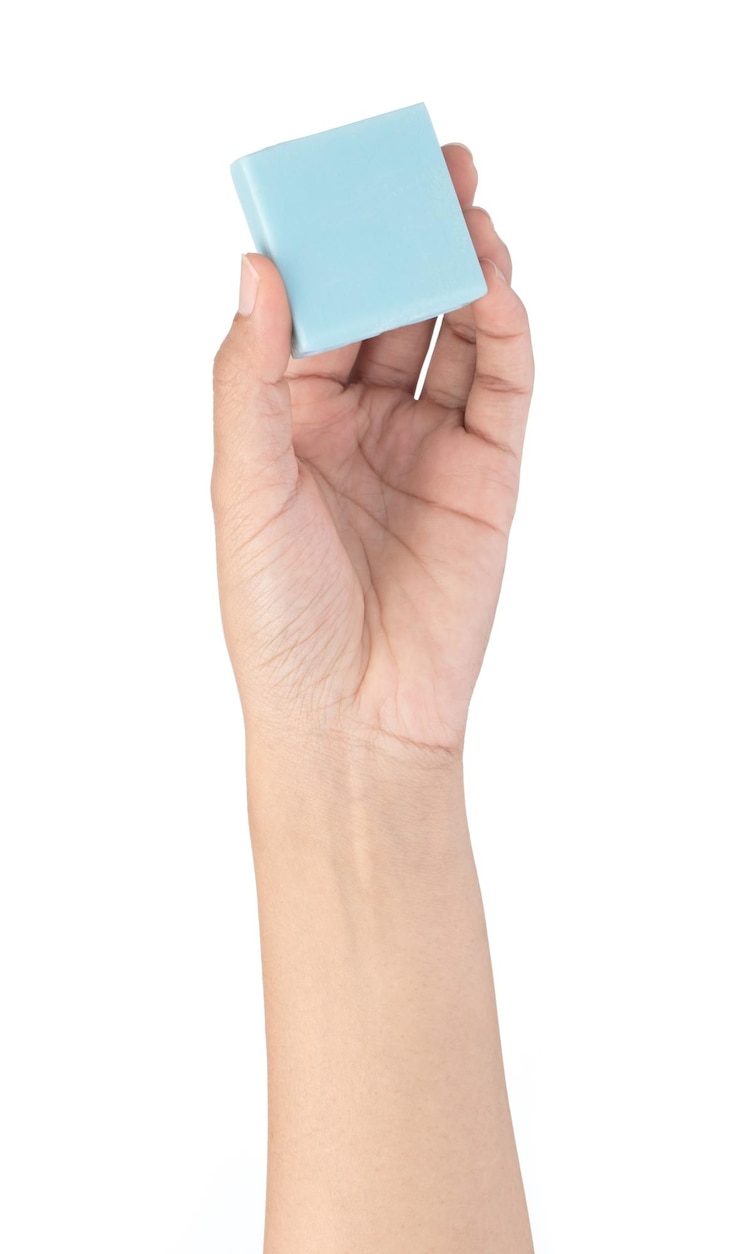 Foto mano sujetando un azul de jabón aislado sobre fondo blanco.
