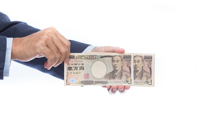 Mano sujetando billetes japoneses sobre fondo blanco. Dinero japonés.