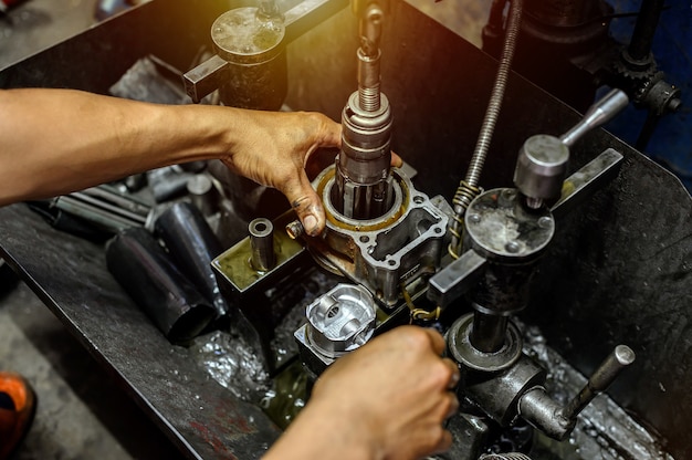 Foto mano sujetando firmemente el cilindro en la máquina bruñidora para motocicleta