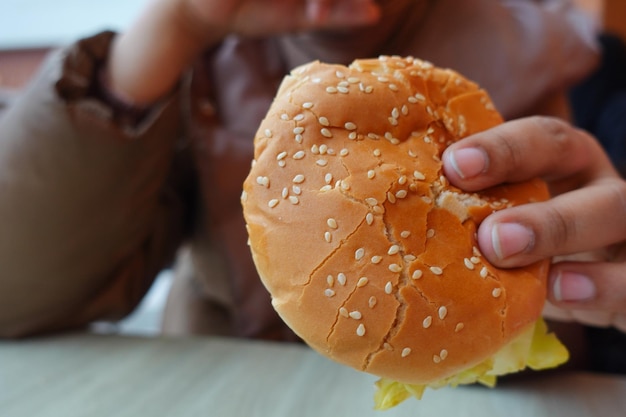 Mano sujetando la hamburguesa de carne en la mesa de cerca