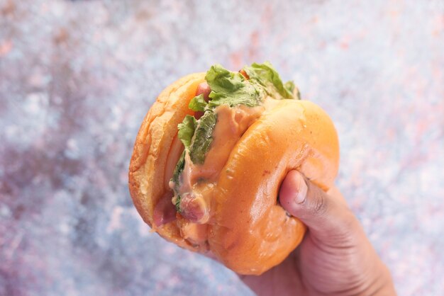 Mano sujetando la hamburguesa de ternera en la mesa de cerca