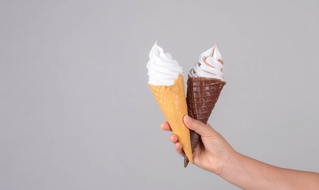 Mano sujetando helado en cono de galleta con fondo de color