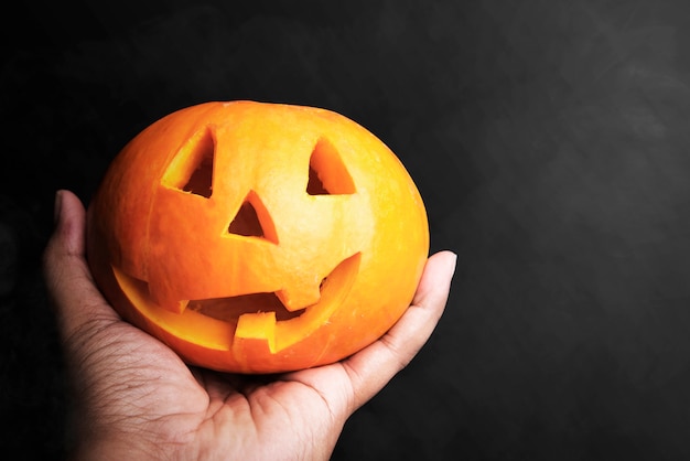 Mano sujetando Jack-o-Lantern con fondo negro