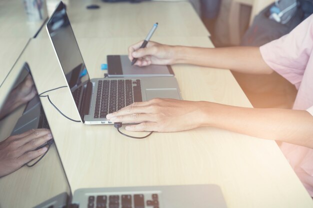 mano sujetando lápiz trabajando en tableta gráfica y computadora