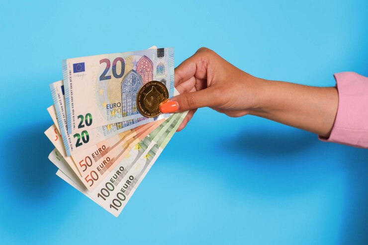 Mano sujetando la moneda del euro y dogecoin sobre fondo azul.