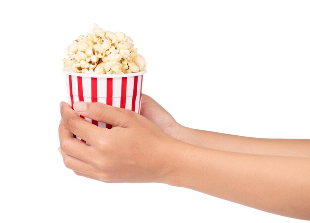 Mano sujetando palomitas de maíz en balde rayado aislado sobre fondo blanco.