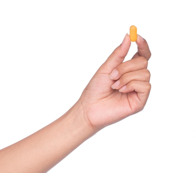 Mano sujetando una pastilla entre el pulgar y el índice aislado sobre fondo blanco.