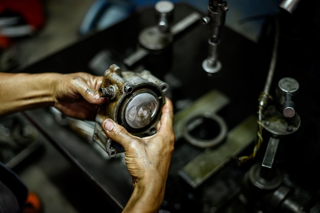 Foto mano sujetando un pistón de motocicleta con máquina borrosa en el fondo