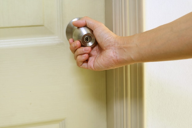 Mano sujetando el pomo de la puerta de acero cerrando la puerta