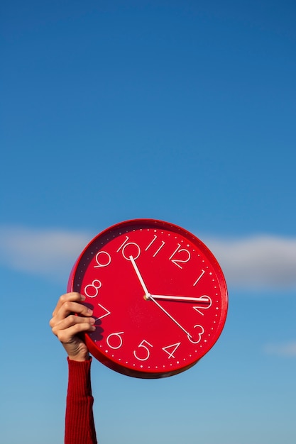 Foto mano sujetando reloj de pared bodegón