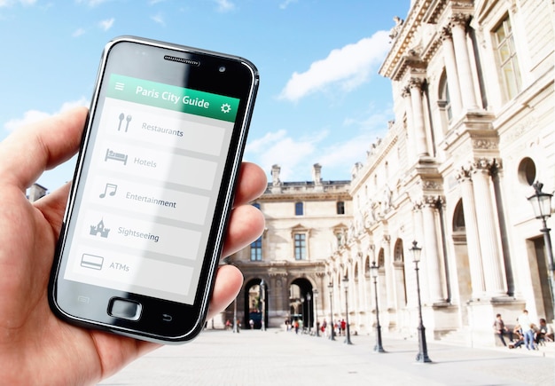 Mano sujetando smartphone con guía de la ciudad de París