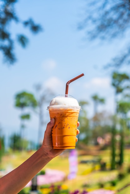 Mano sujetando la taza de té helado de leche tailandesa