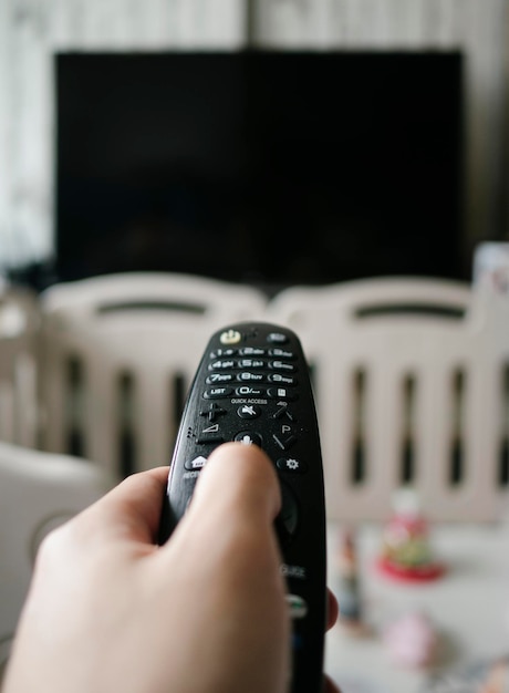 Mano sujetando la televisión apuntando a distancia con bolígrafo y juguetes