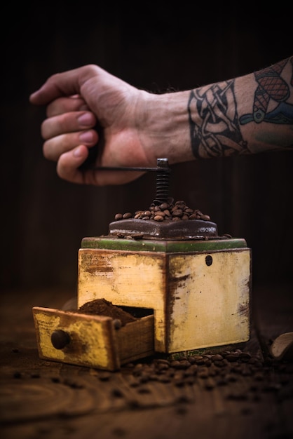 Mano tatuada y molinillo de café.