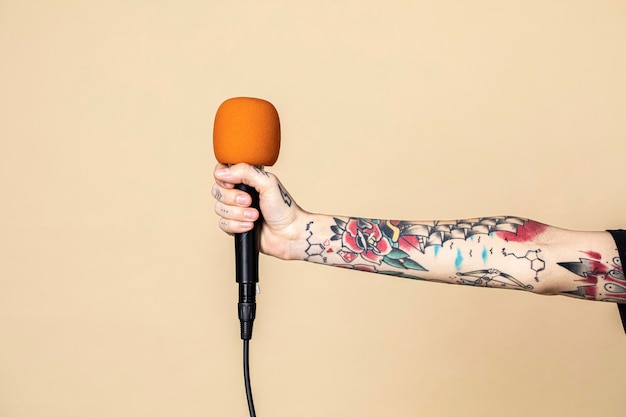 Mano con tatuado sosteniendo un micrófono