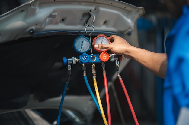 La mano del técnico mecánico de automóviles usa el medidor para verificar el problema de calor del sistema de aire acondicionado del automóvil y solucionar la reparación y el llenado de refrigerante de aire